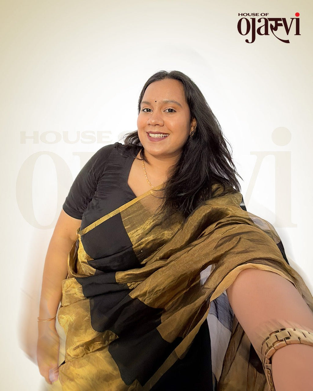Smiling model twirling in the black Chanderi handwoven saree, showcasing the dramatic golden zari pallu drape.