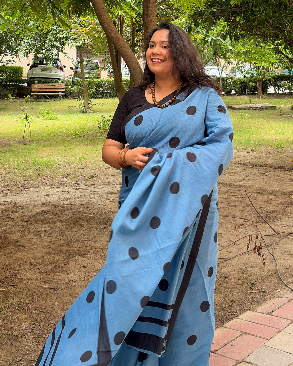 Side portrait of a model showcasing the soft cotton weave and bold polka dot pattern of the blue handwoven saree by House of Ojasvi