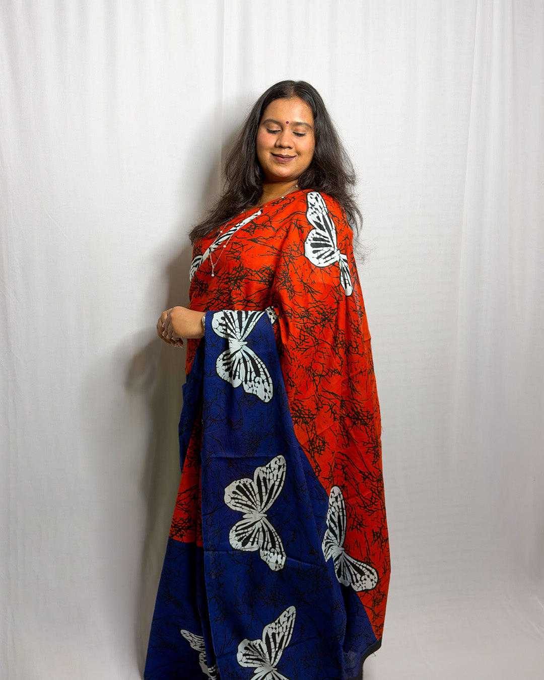 Three-quarter drape view of the orange and royal blue butterfly print handwoven cotton saree showing the cascading printed pallu
