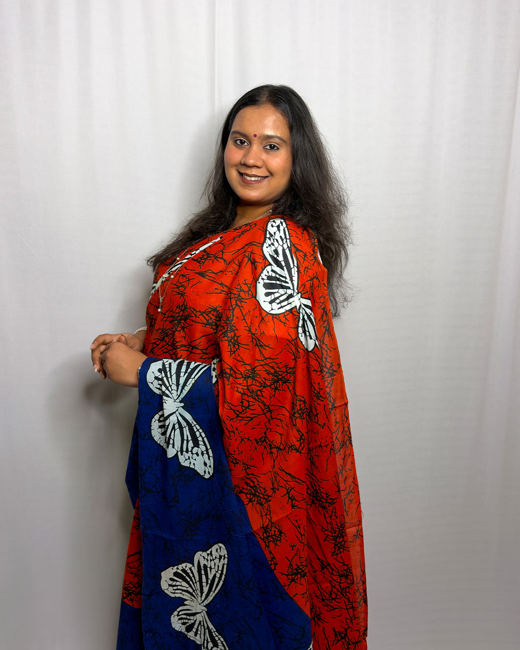 Model smiling in the blue and orange butterfly print handwoven cotton saree with batik crackle texture by House of Ojasvi