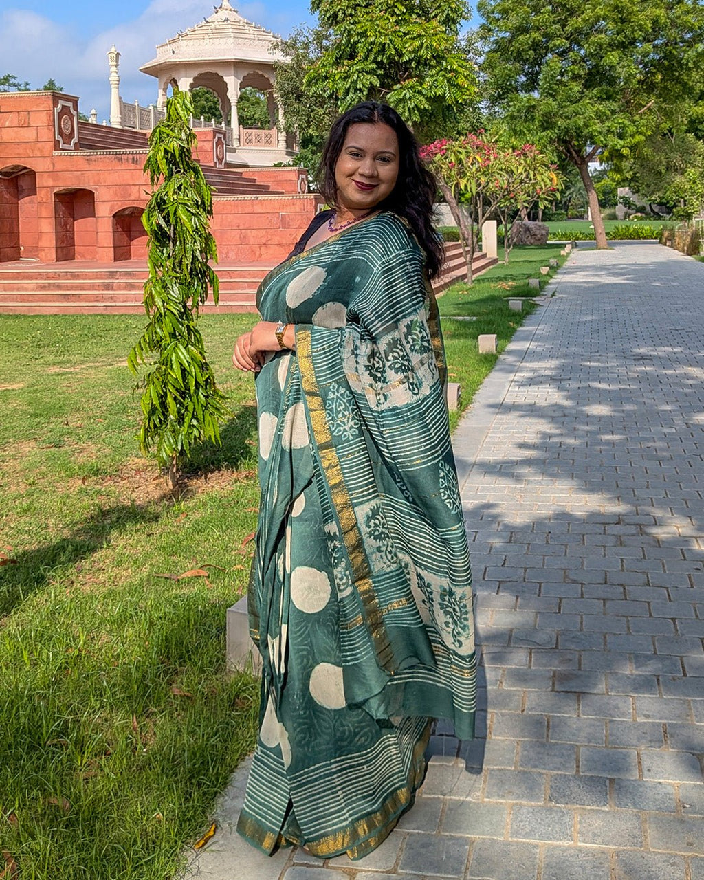 Detailed view showing traditional block-print style motifs and stripes on the dark green Maheshwari saree.