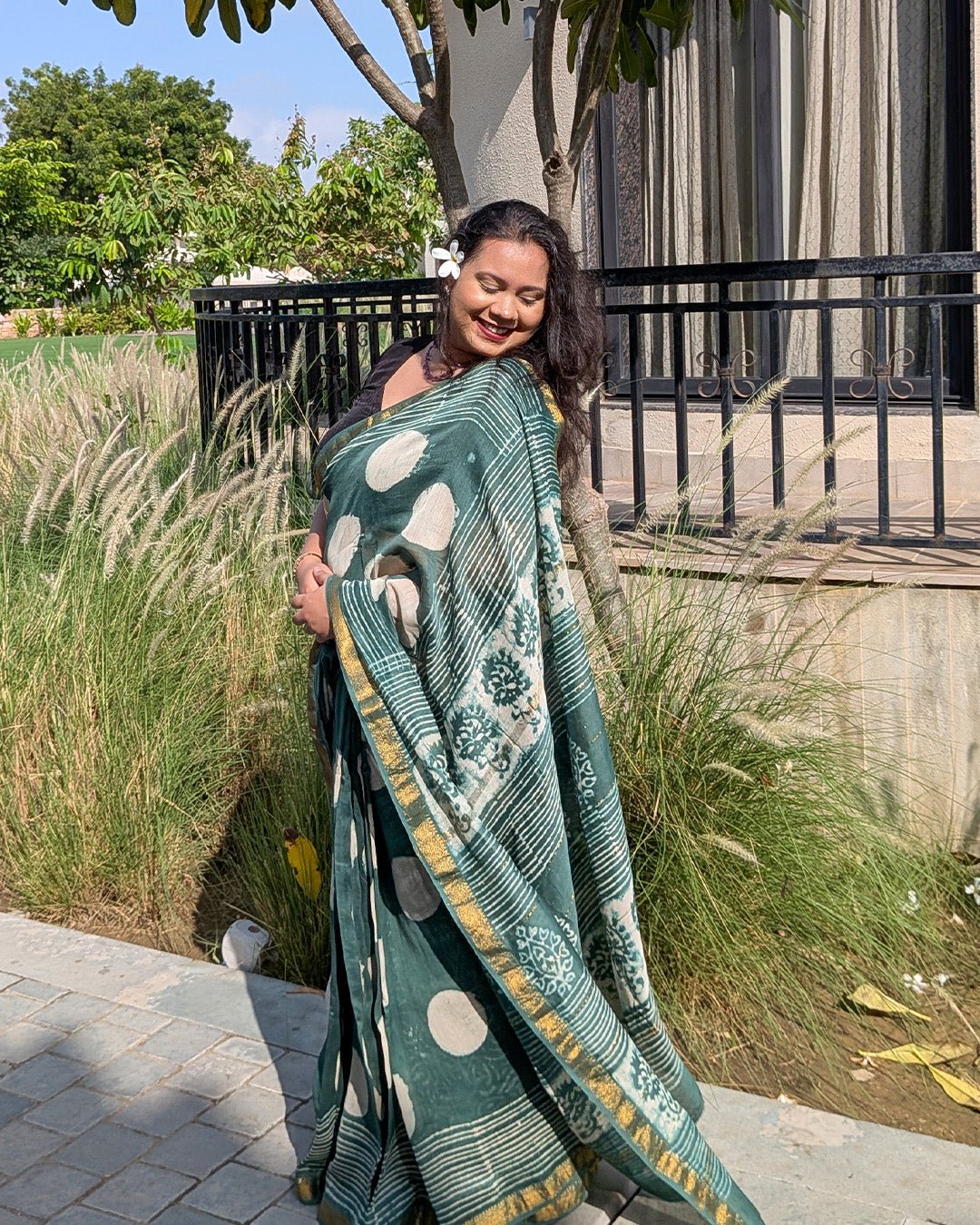 Garden view of a model styling the dark green polka dot Maheshwari handwoven saree.