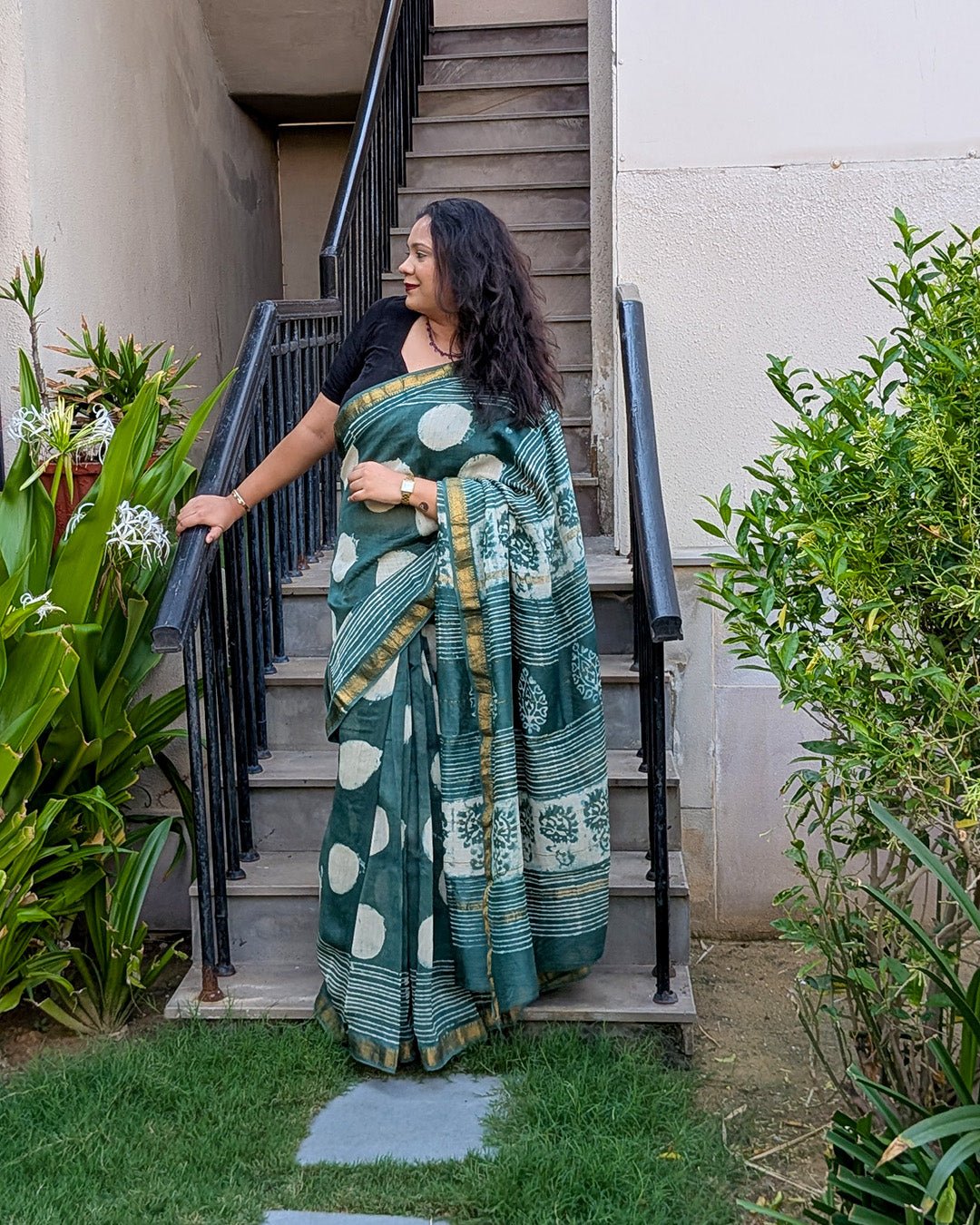 Close-up view of the patterned pallu and gold zari border on the dark green Maheshwari saree.