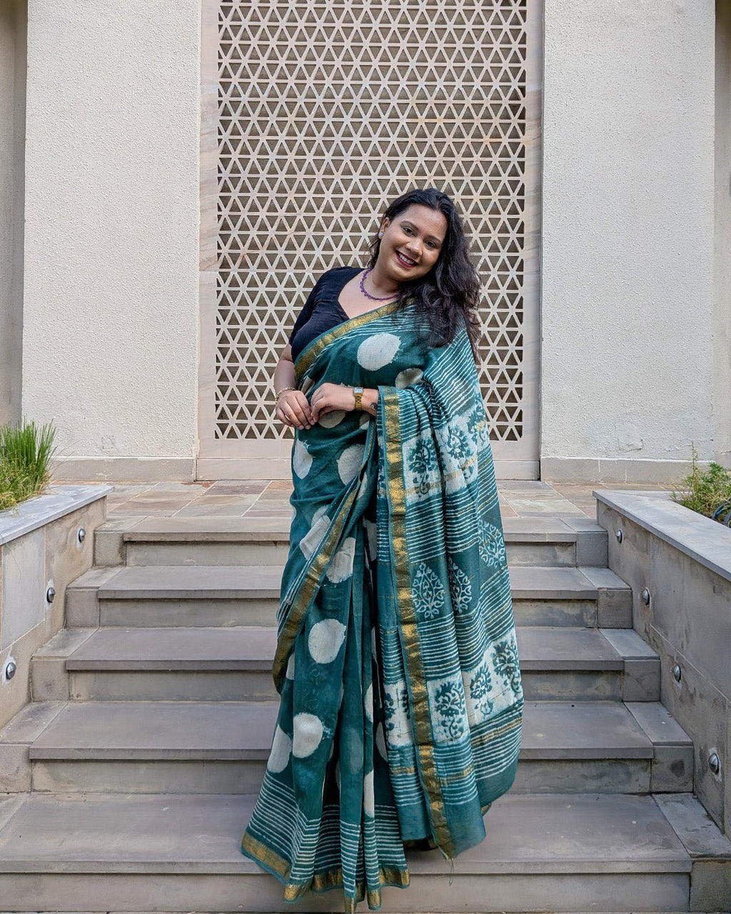 Outdoor lifestyle view of the dark green polka dot handwoven Maheshwari saree.