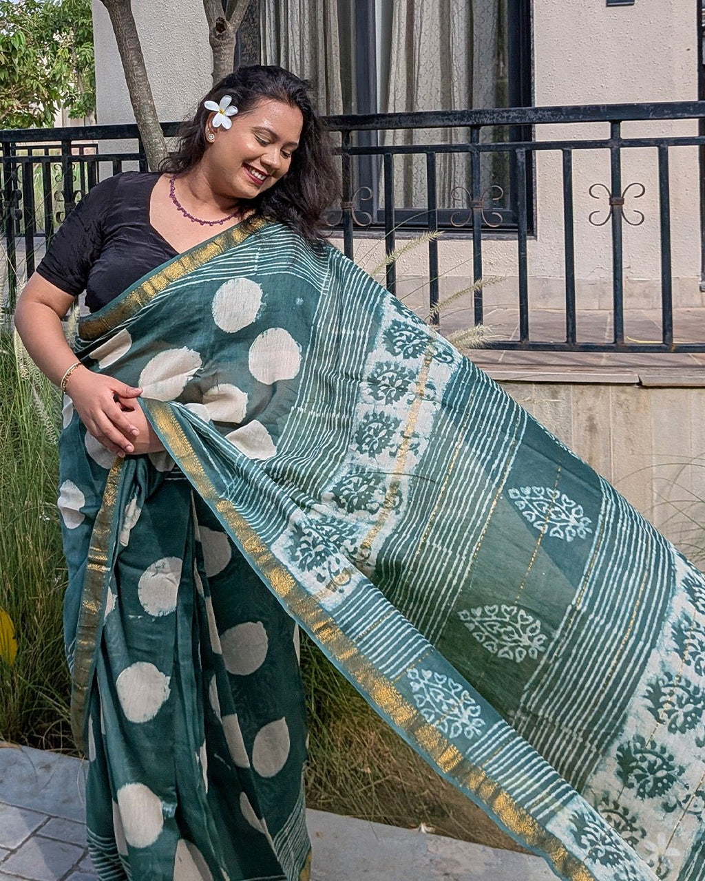 Close-up portrait of model wearing the dark green polka dot Maheshwari handwoven saree.