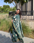 Model posing on stairs wearing the dark green polka dot handwoven Maheshwari saree by House of Ojasvi.