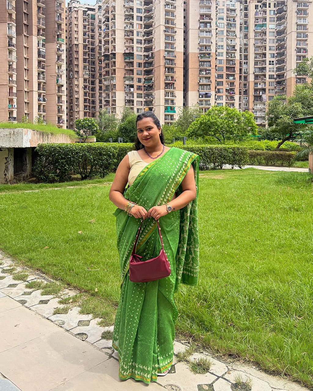 Model standing in a lush green garden wearing the vibrant green Chanderi handwoven saree with cream butis by House of Ojasvi.
