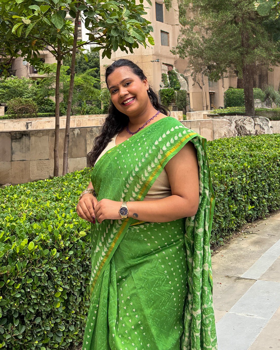 Smiling close-up showing the fine texture of the green Chanderi fabric, cream buti motifs, and golden-yellow border.