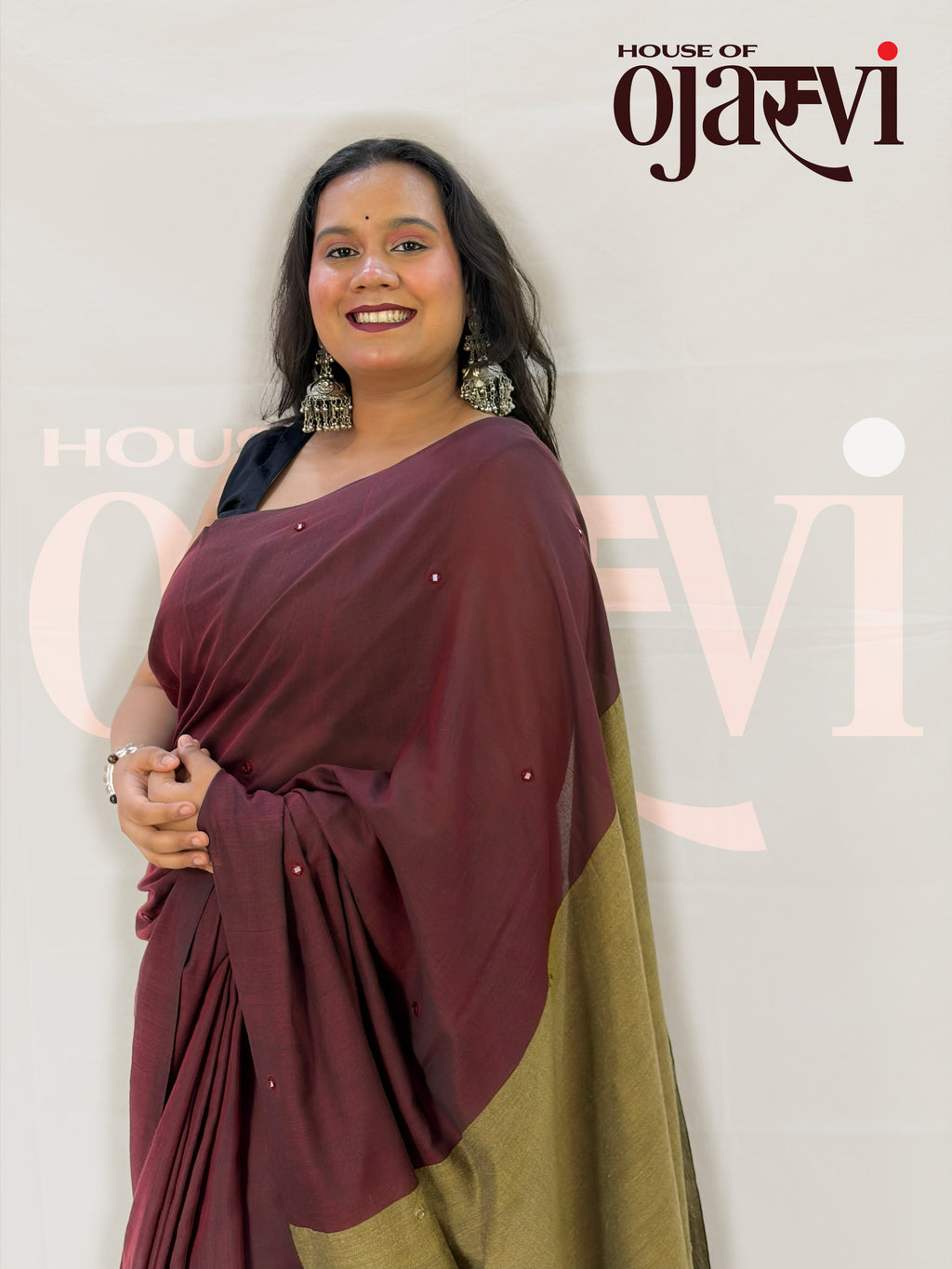 Waist-up portrait showing the fluid maroon cotton drape, subtle mirror-sequin butis, and contrasting gold pallu border