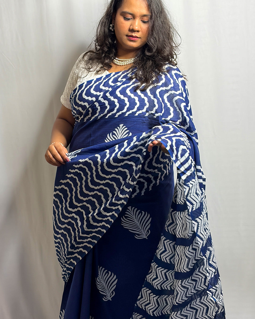 Model showcasing the scalloped wave border and botanical leaf motifs on the navy blue block-print cotton saree by House of Ojasvi