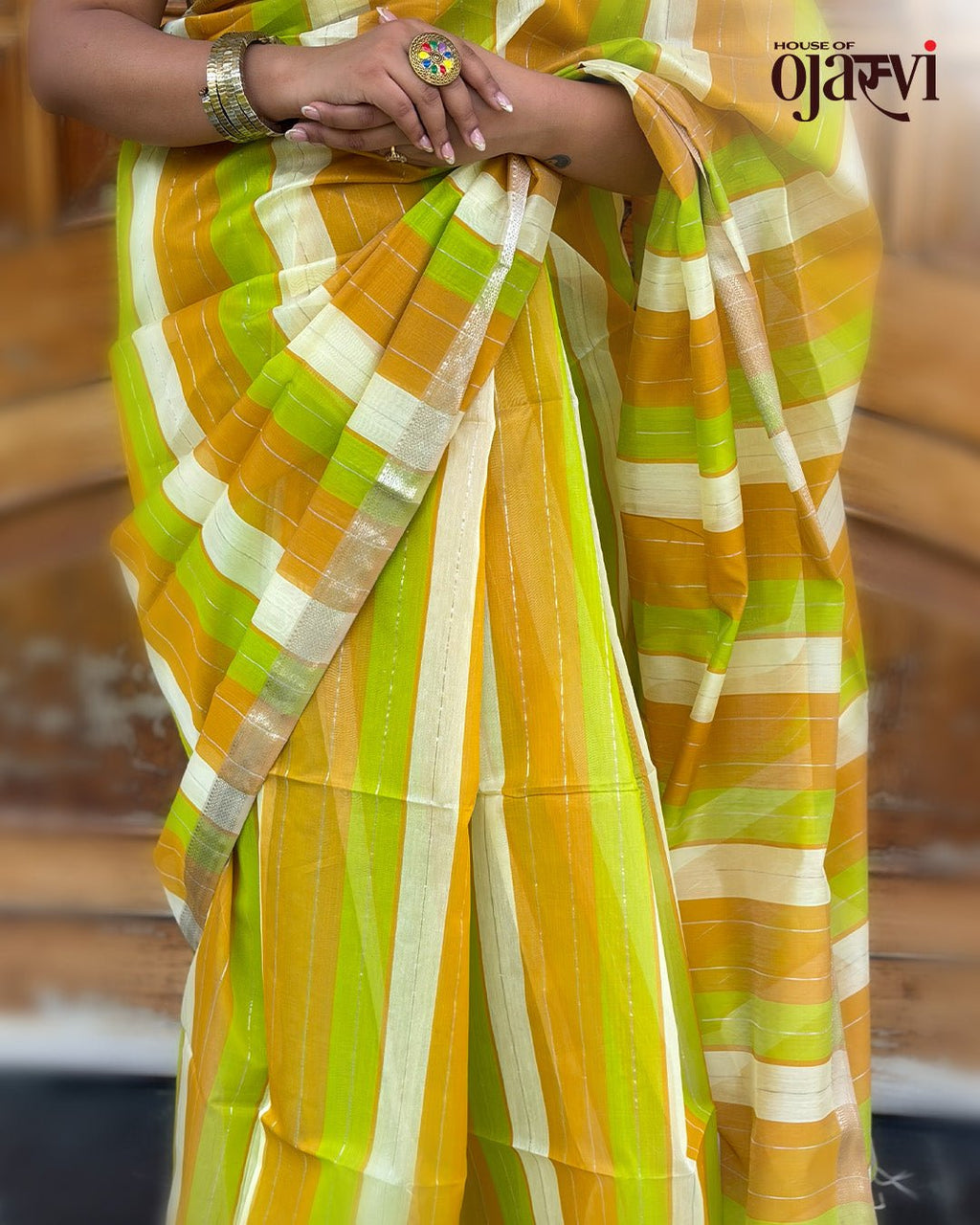 Portrait of a model smiling while styling the orange and green striped Maheshwari handwoven saree