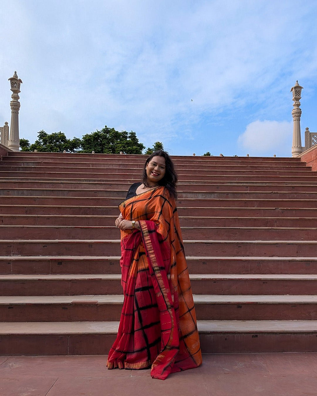Outdoor lifestyle view showcasing the fluid drape and vibrant check pattern of the Maheshwari handwoven saree.