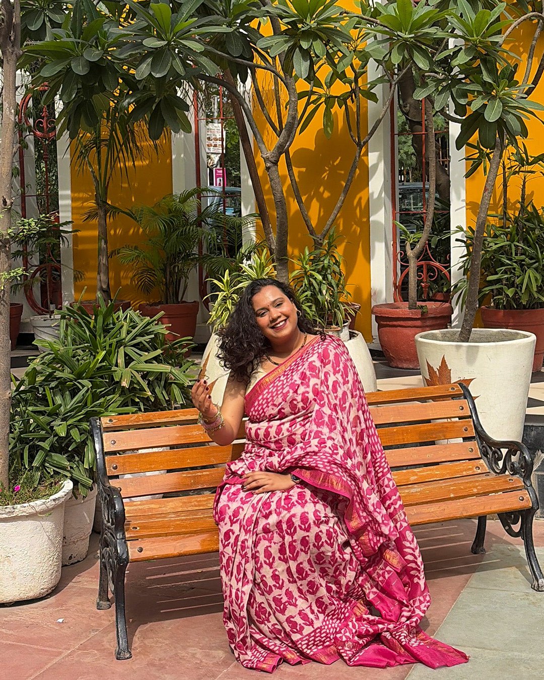 Model posing in front of a traditional arched wooden door wearing the pink and white Maheshwari saree.