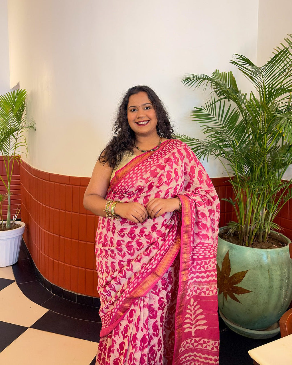 Outdoor garden view of a model styling the pink and white handwoven Maheshwari saree.