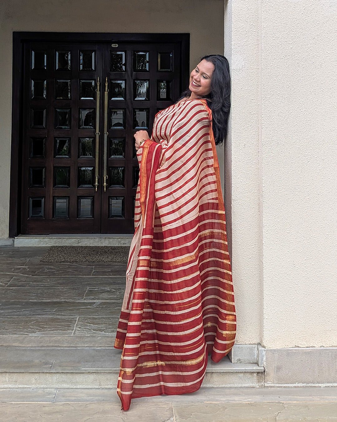 Lifestyle view showcasing the fluid drape and traditional gold zari borders of the Maheshwari handwoven saree.