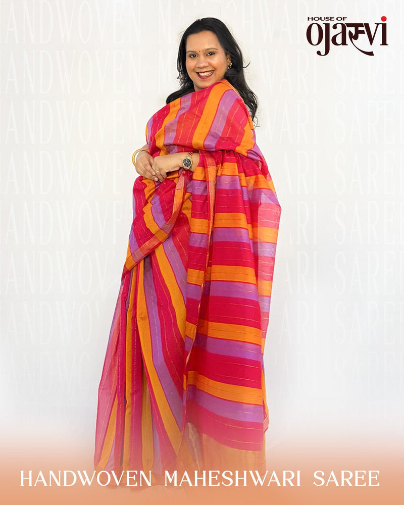 Model posing in a studio setting wearing the red and orange striped Maheshwari handwoven saree by House of Ojasvi.