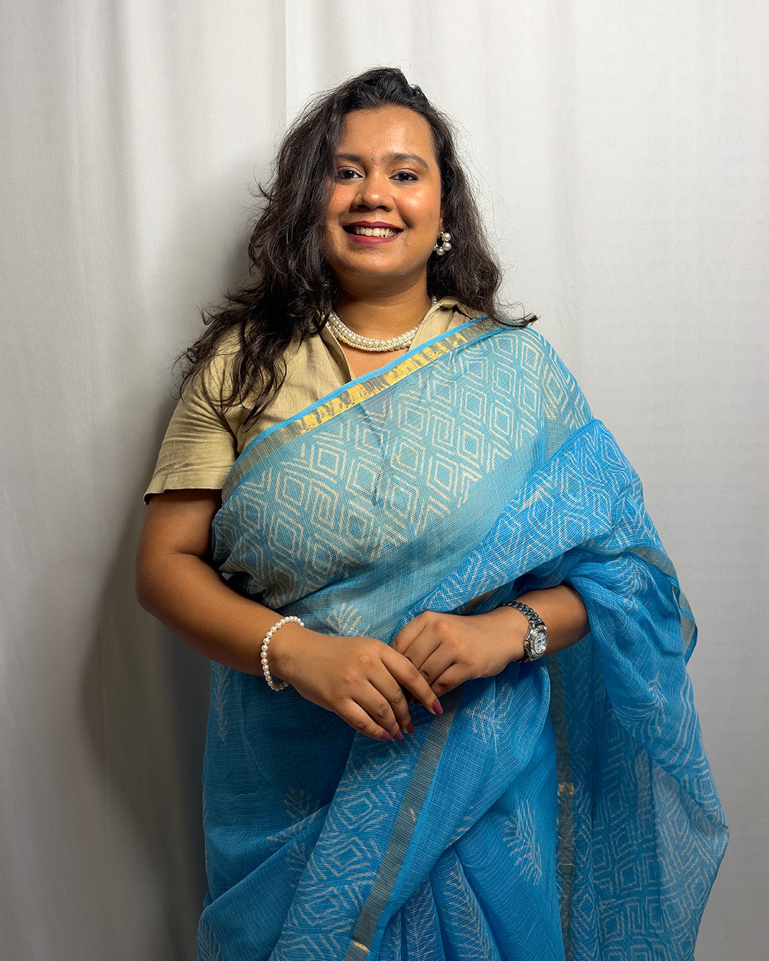 Model wearing the sky blue block-print handwoven Kota Doria saree with a beige collared blouse and pearl jewellery by House of Ojasvi