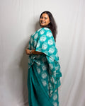 Model showcasing the white meditating Buddha motifs on the teal green handwoven cotton saree by House of Ojasvi