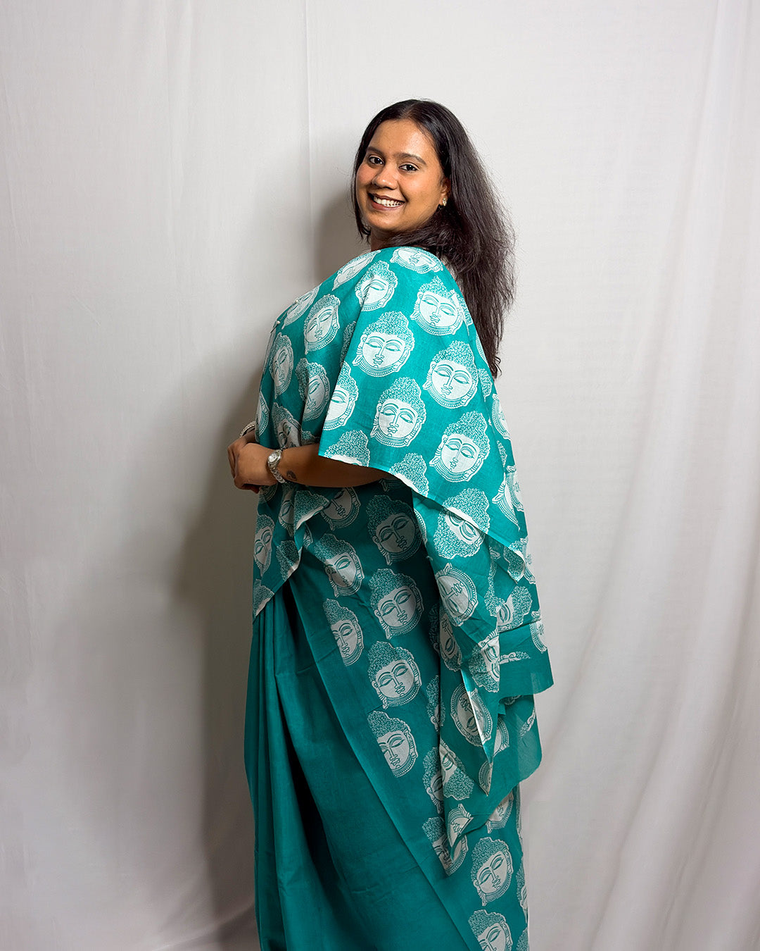 Model showcasing the white meditating Buddha motifs on the teal green handwoven cotton saree by House of Ojasvi