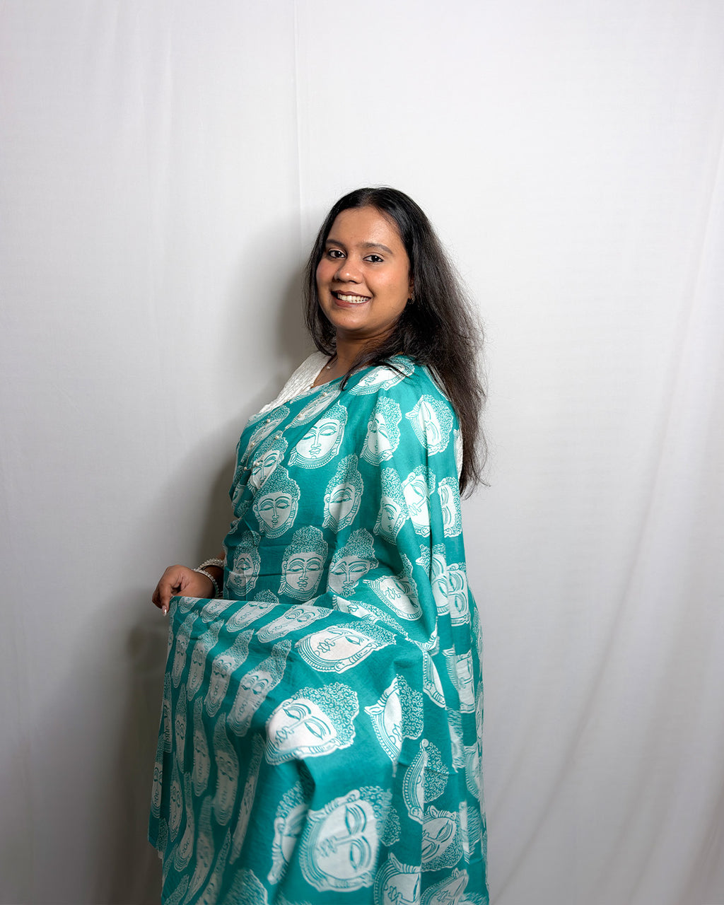 Side drape view of the teal green and white Buddha print cotton handwoven saree showing the solid teal pleats and printed pallu